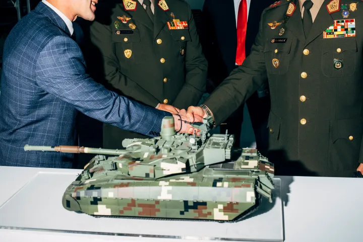 Das Foto zeigt einen Handschlag zwischen Geschäftspartnern auf einer internationalen Waffenmesse, ohne die Handelnden individuell sichtbar zu machen