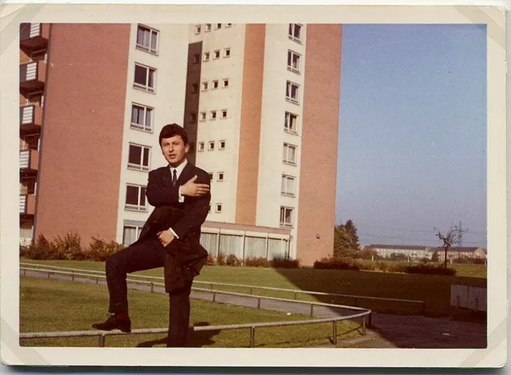 Onur Dülger vor dem Ford-Arbeiterwohnheim am Tag seiner Trauung Köln-Buchheim, Gronauer Straße, 23.12.1965 „Ein Mitbewohner im Heim hat fotografiert und dann die Fotos für 50 Pfenning verkauft. An dem Tag war ich so glücklich, weil Monika und ich es endlich geschafft haben, eine notarielle Erlaubnis zu bekommen, um heiraten zu dürfen. Auf dem Weg zum Rathaus habe ich diesem Fotografen gesagt: ‚Mach schnell ein Foto, ich muss weg.‘“ (Onur Dülger) © Onur Dülger/DOMiD-Archiv, Köln